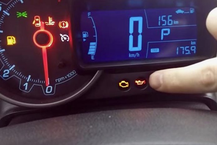 Automobilio prietaisų skydelis su užsidegusia alyvos lygio lempute ir rodykle, nukreipiančia į ją.